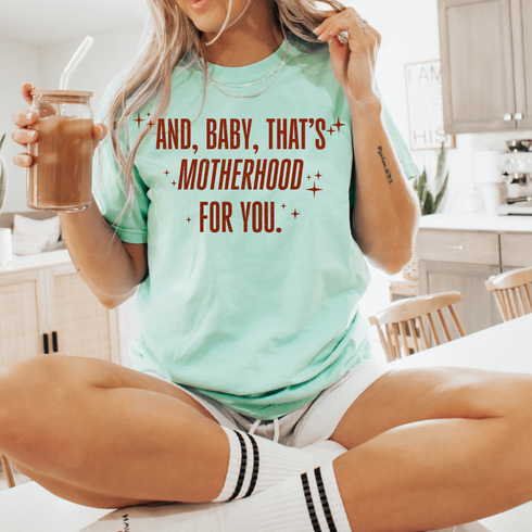 mom holding ice coffee wearing graphic shirt inspired by showgirl era, taylor swift